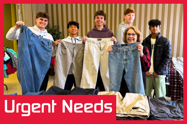 A group of volunteers pose for a photo with pairs of jeans they are collecting for a donation drive. The text "Urgent Needs" is displayed in a red box at the bottom of the image.