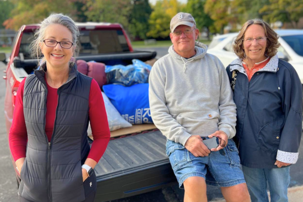Donate – Clothing Clothing volunteers from Midland's Open Door stand in front of a truck filled with clothing donations.