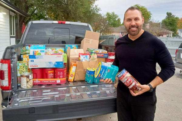 Donate – Food Image of a truck bed full of food and a representative from Weed Man Midland dropping off a donation at the Open Door community soup kitchen.